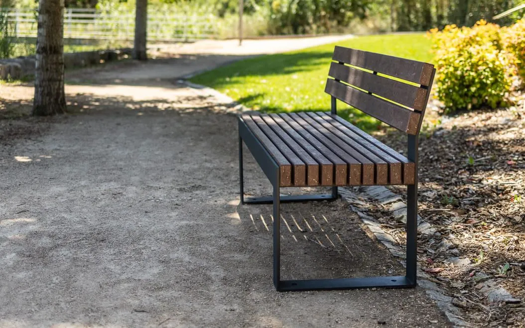 Banco urbano durável colocado em parque urbano com encosto da linha Frame da Floema, feito de plástico 100% reciclado e reciclável.