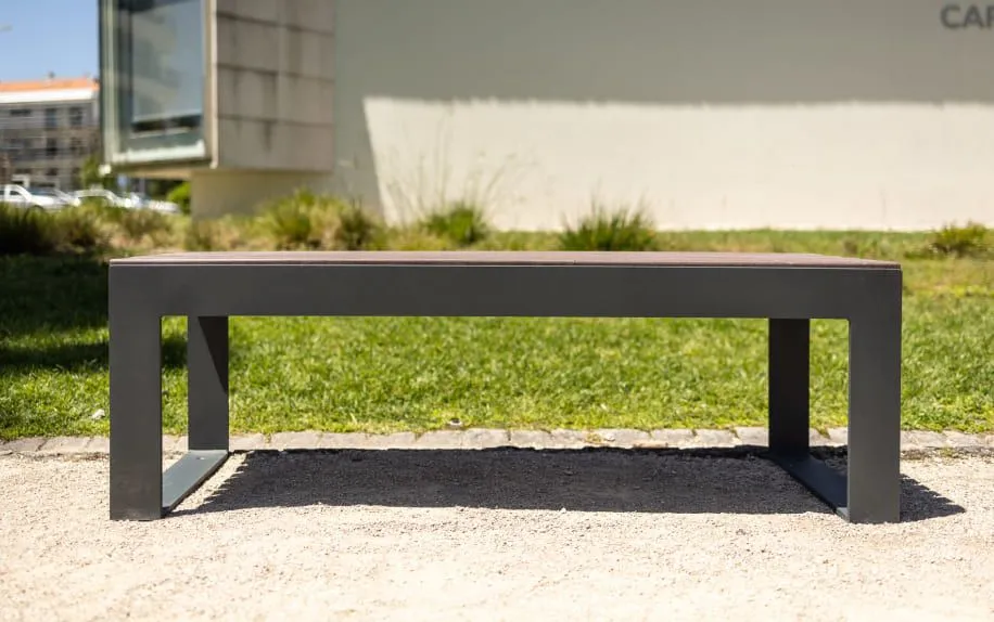 Vista frontal de um banco durável e sem necessidade de manutenção, sem encosto, ideal para espaços urbanos comuns.