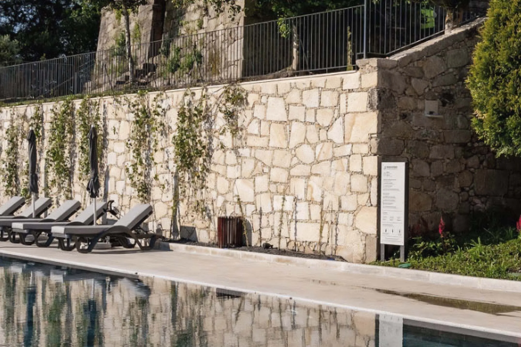 Área de piscina de exterior de hotel com totem informativo em HPL+ e plástico reciclado.