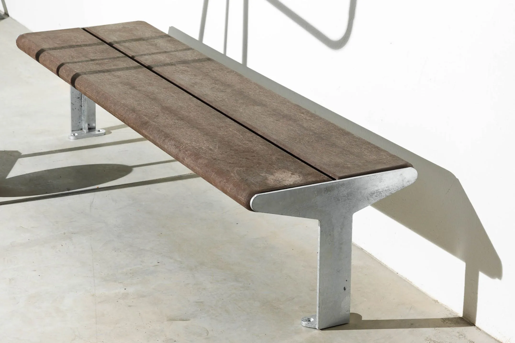 Banco sem costas da linha Reuse, coleção Floema Urban, com estrutura em aço galvanizado e tábuas em plástico reciclado castanho.