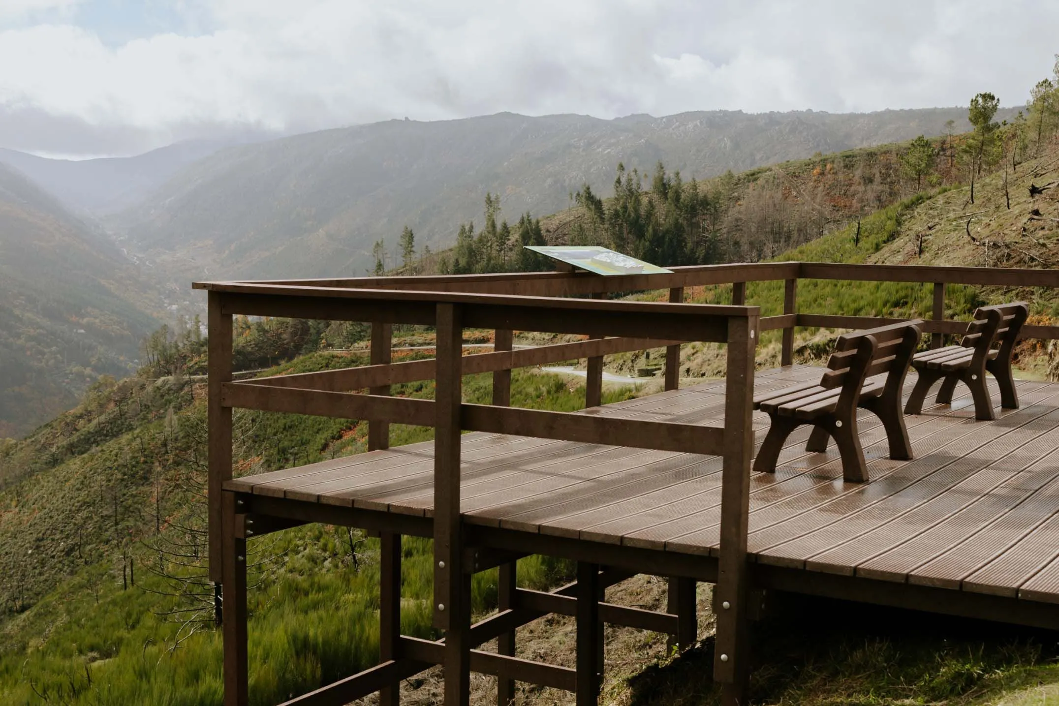 Miradouro com bancos em plástico reciclado castanho Floema. Incluída mesa interpretativa modelo Floema em HPL Print. Montanhas da Serra da Estrela no fundo.