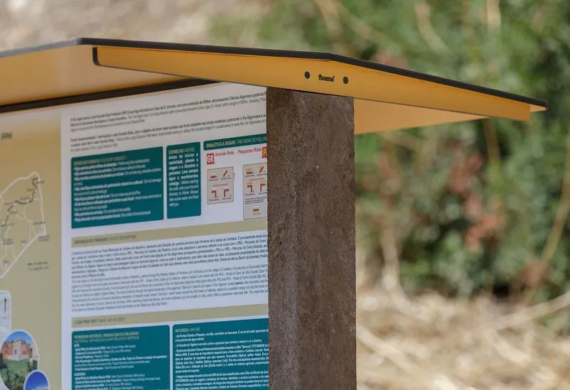 Detalhe de painel informativo com telhado modelo Floema, para áreas naturais. Estrutura em plástico reciclado castanho, telhado em HPL e painel em HPL Print.