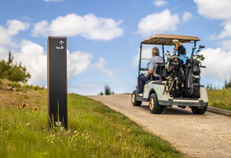 Totem direcional Royal para campo de golfe em plástico reciclado e HPL+. Encaminhamento de buggy de golfe com sacos e jogadores.