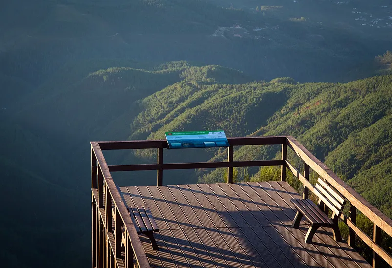 Mesa interpretativa em HPL Print em miradouro de plástico reciclado castanho em área natural, ambos produtos Floema.