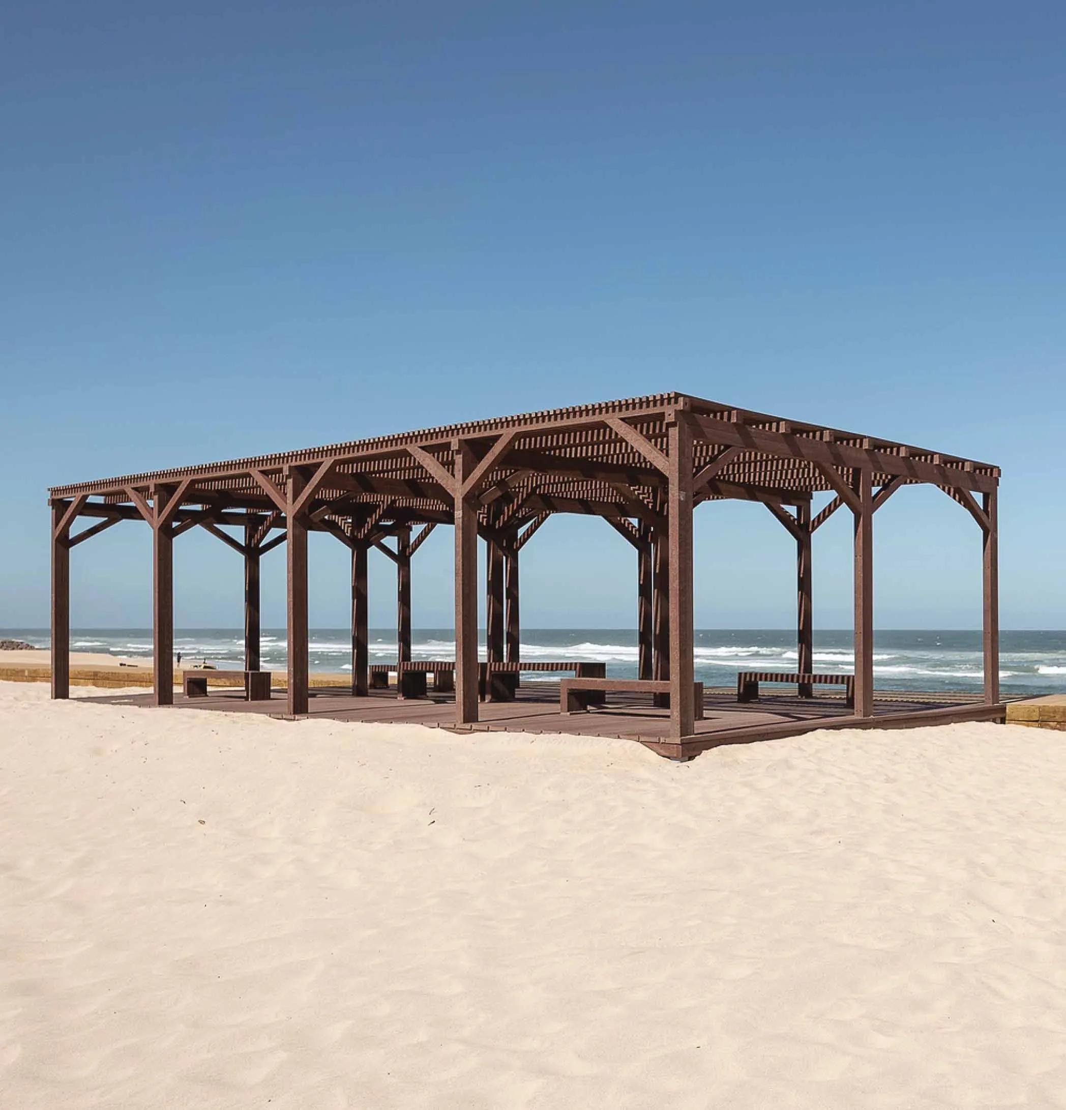Pérgula em plástico reciclado castanho Floema com bancos em plástico reciclado em praia.