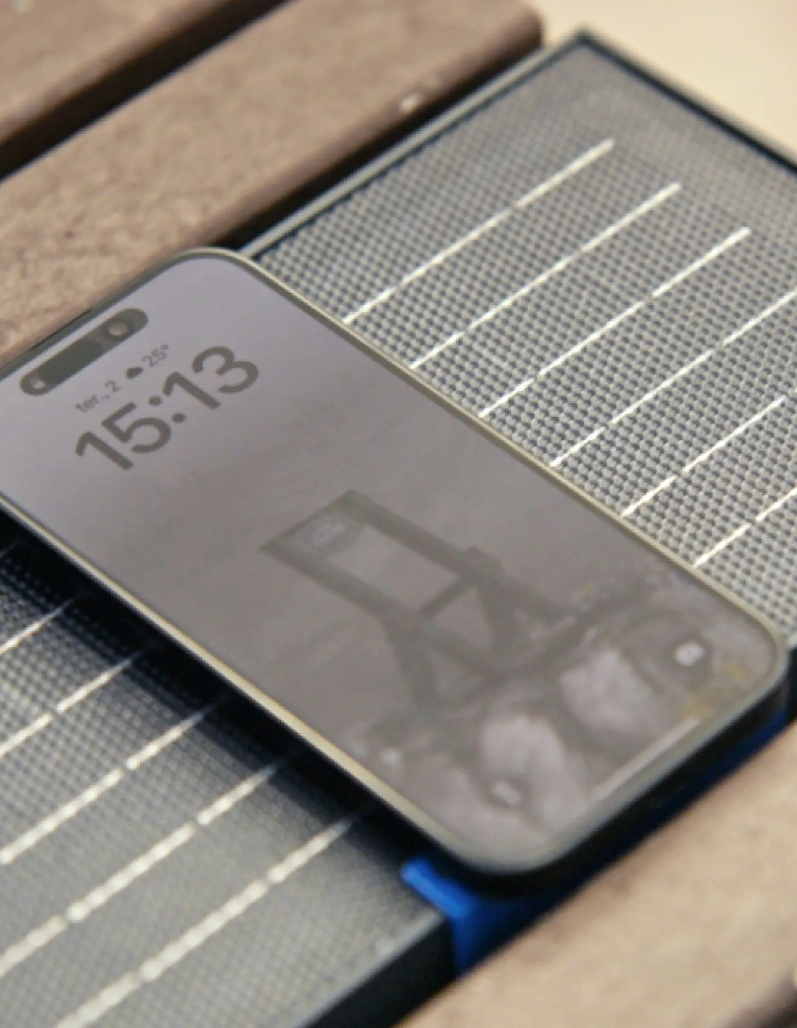 Close-up do telemóvel a carregar num banco inteligente, mostrando perfis de plástico reciclado e módulo de carregamento solar.