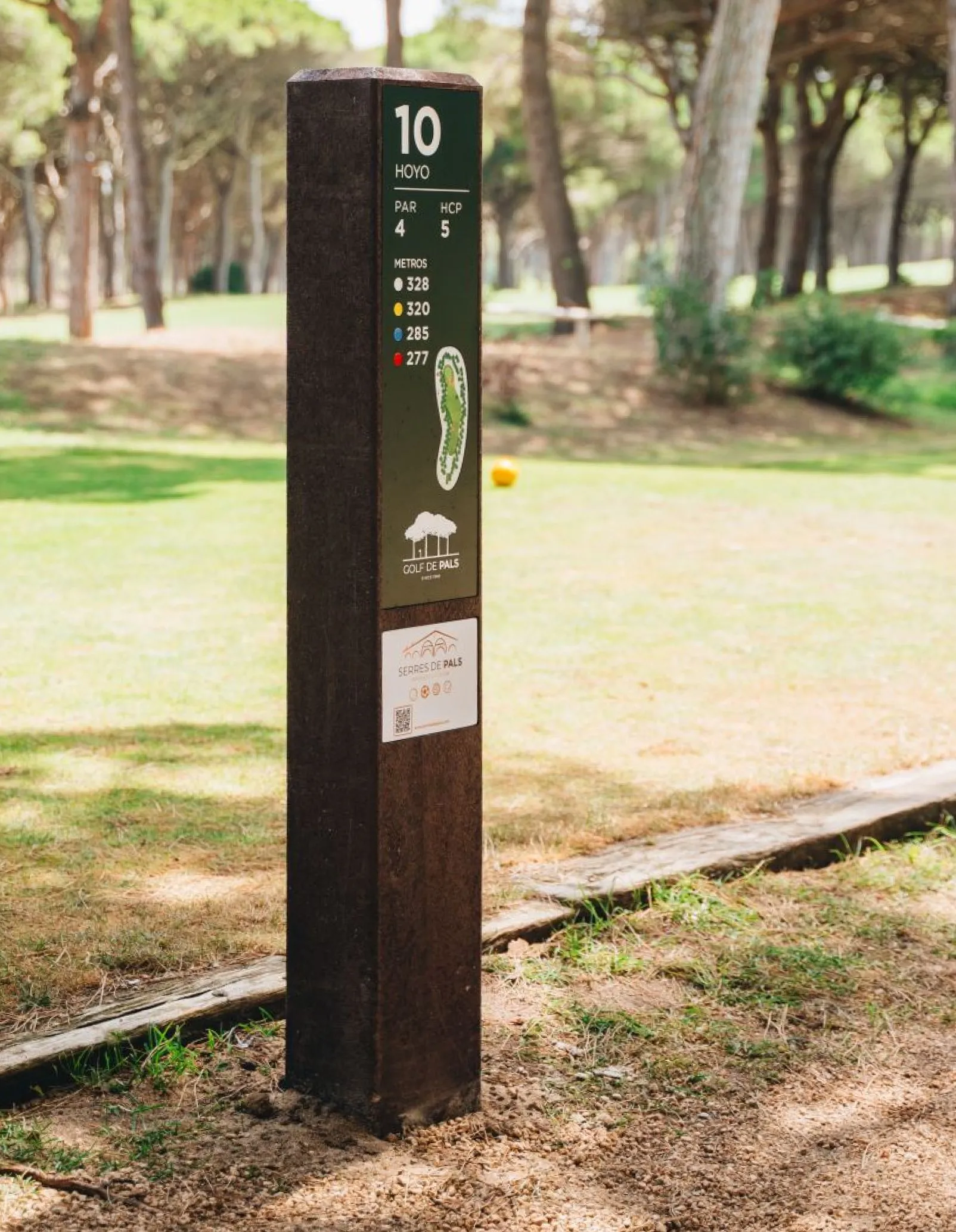 Tee totem Royal em área de tee em campo de golfe. Com estrutura em plástico reciclado castanho e HPL+ e com uma pequena área de publicidade. 